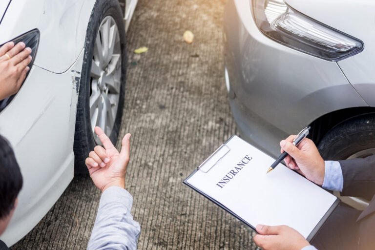 Insurance agent writing on clipboard while examining car after a