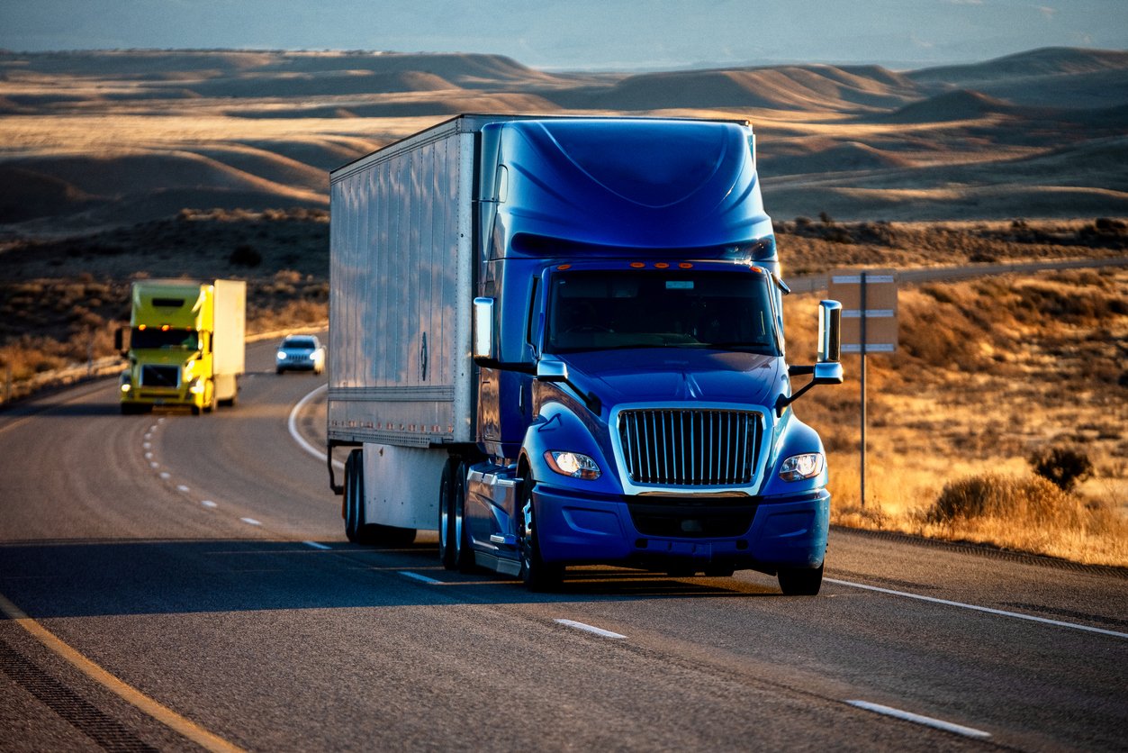 Long Haul Semi-Truck Rolling Down a Four-Lane Highway at Dusk